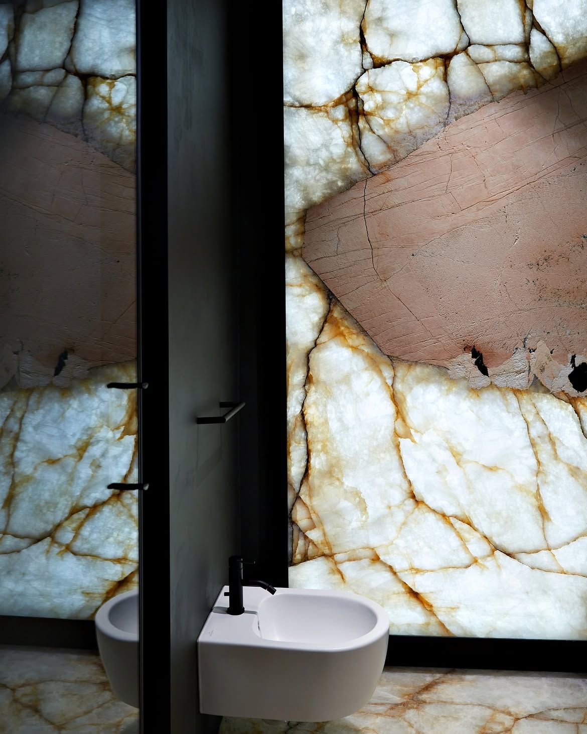 Parete bagno in quarzite Patagonia retroilluminata: la luce attraversa la lastra accanto allo specchio
