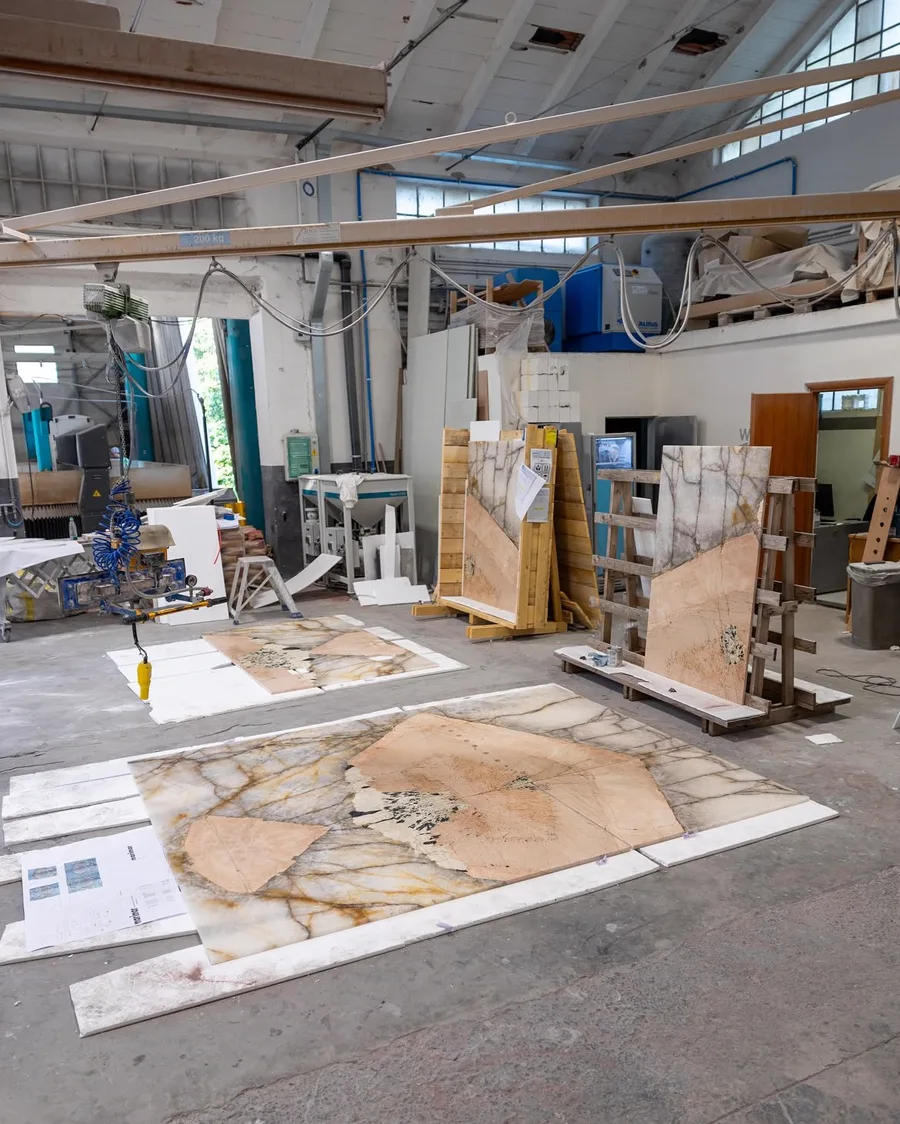 Laboratorio Savoia Marmi durante un Dry Lay: pannelli in quarzite a terra e sui cavalletti, con i disegni di nesting sul pavimento