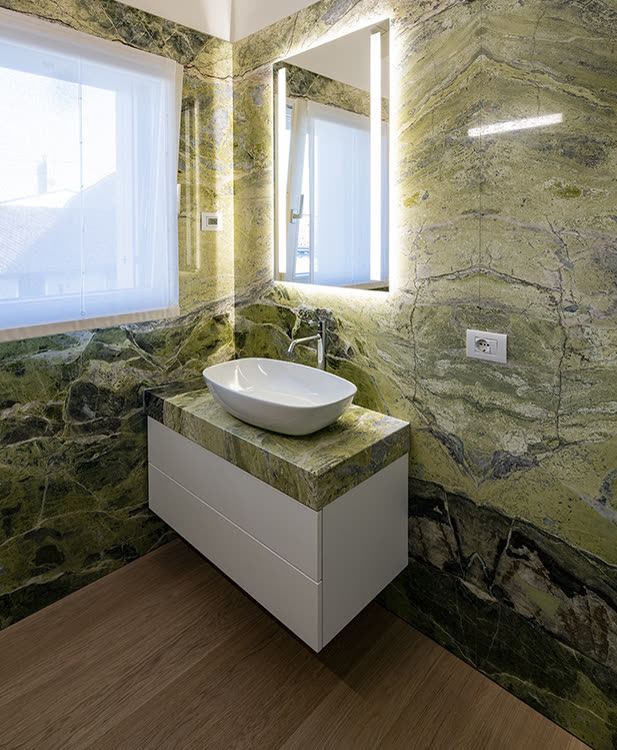 Bathroom clad in bookmatched Irish Green marble