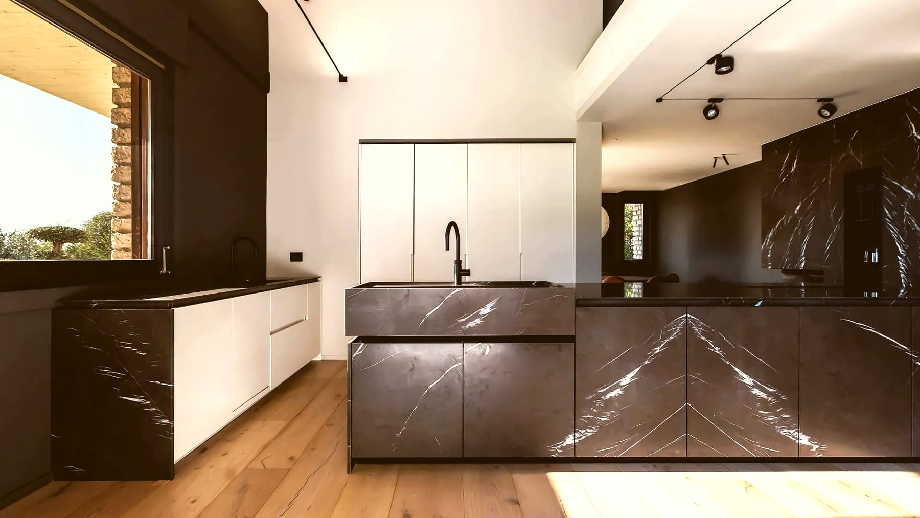 Isola cucina in marmo Grafite Grey con lavello scavato nella lastra e boiserie interna in legno